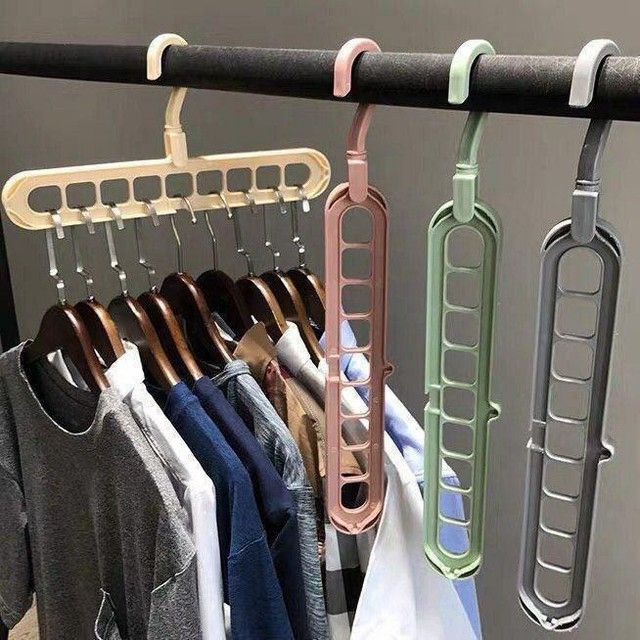 Multiple multi-hook hangers in different colors hanging on a rod with clothes.